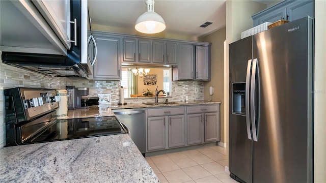 kitchen with tasteful backsplash, stainless steel appliances, decorative light fixtures, light tile floors, and sink