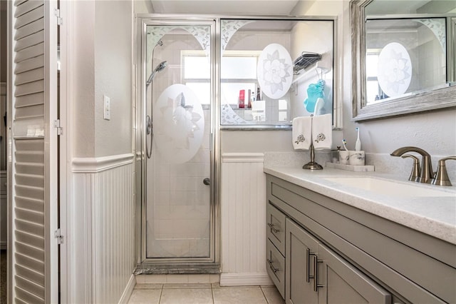 bathroom featuring a shower with door, tile flooring, and vanity with extensive cabinet space