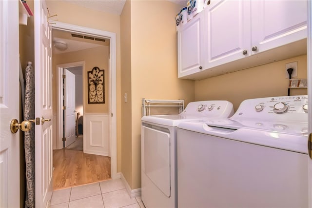 laundry area with independent washer and dryer, light hardwood / wood-style flooring, and cabinets