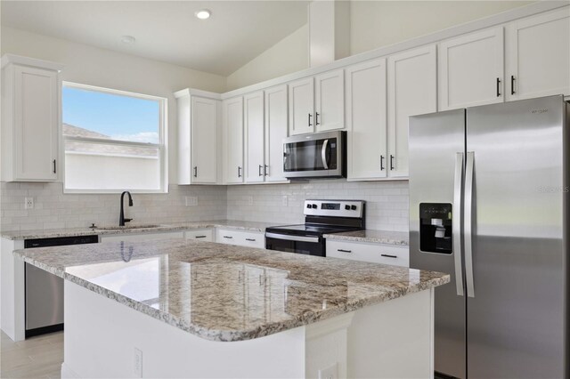 kitchen with appliances with stainless steel finishes, sink, white cabinetry, and a kitchen island