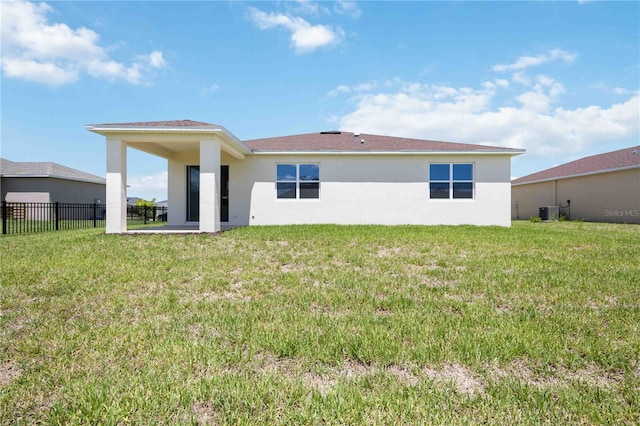 rear view of property featuring central AC and a lawn