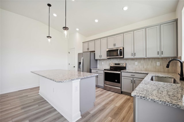 kitchen with vaulted ceiling, a kitchen island, decorative light fixtures, sink, and stainless steel appliances