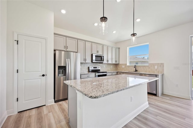 kitchen with pendant lighting, sink, a center island, light stone counters, and stainless steel appliances