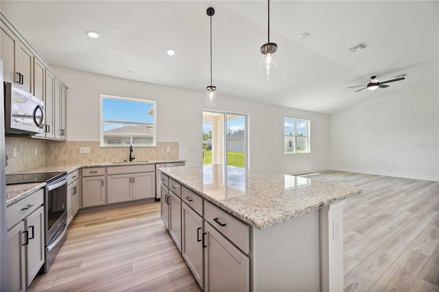 kitchen featuring appliances with stainless steel finishes, tasteful backsplash, sink, hanging light fixtures, and a center island