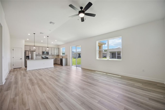 unfurnished living room featuring ceiling fan, sink, and light hardwood / wood-style flooring