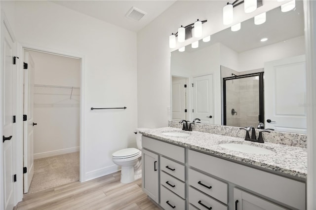 bathroom featuring vanity, toilet, a shower with door, and wood-type flooring