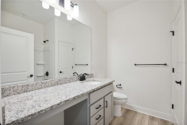 bathroom with vanity, hardwood / wood-style flooring, toilet, and walk in shower