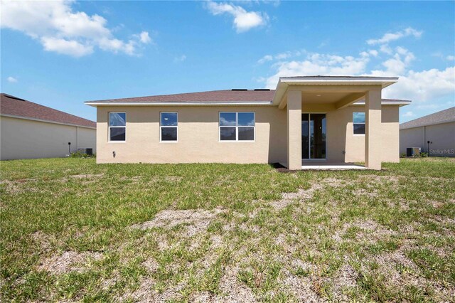 rear view of house with a yard and central AC