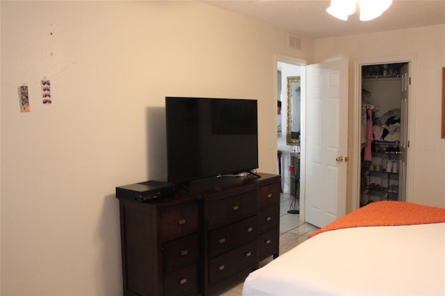 bedroom with a walk in closet, a closet, and light tile floors