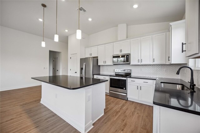 kitchen with appliances with stainless steel finishes, light hardwood / wood-style flooring, sink, backsplash, and a kitchen island