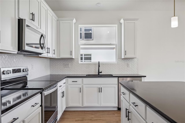 kitchen featuring white cabinetry, stainless steel appliances, sink, light hardwood / wood-style floors, and backsplash