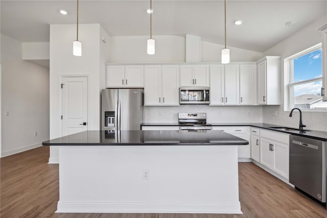 kitchen featuring stainless steel appliances, a kitchen island, tasteful backsplash, and sink