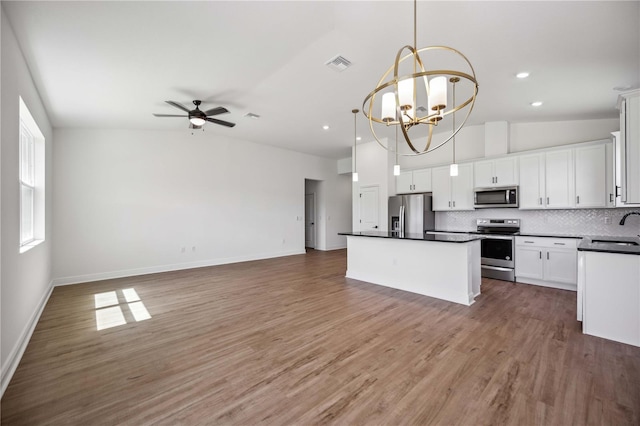 kitchen with white cabinetry, stainless steel appliances, ceiling fan with notable chandelier, and hardwood / wood-style flooring