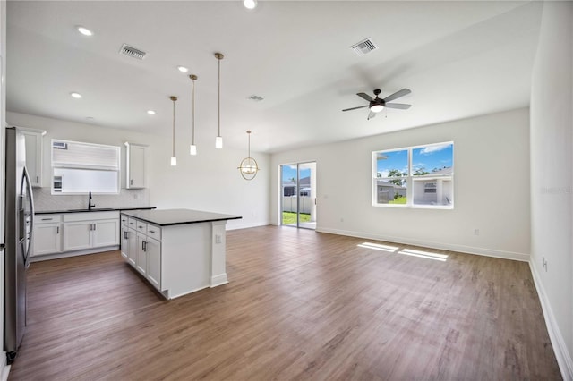 kitchen with decorative backsplash, dark wood-type flooring, white cabinetry, and a kitchen island