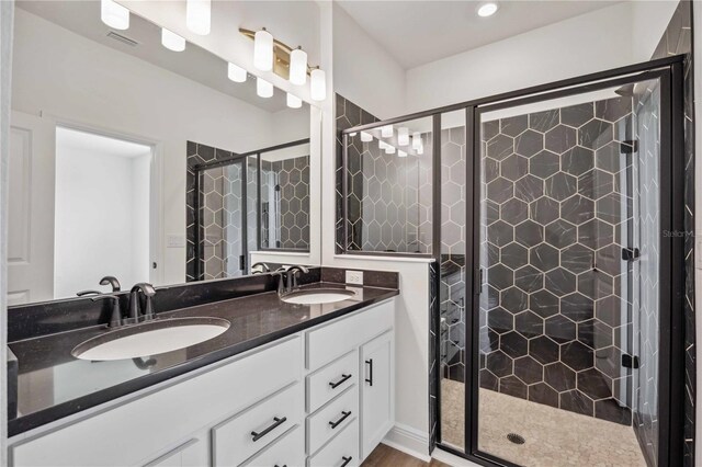 bathroom featuring a shower with door and double vanity