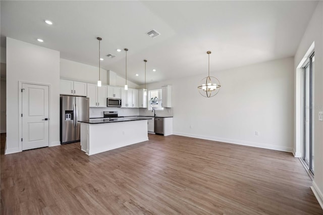 kitchen featuring stainless steel appliances, hanging light fixtures, a kitchen island, white cabinetry, and wood-type flooring