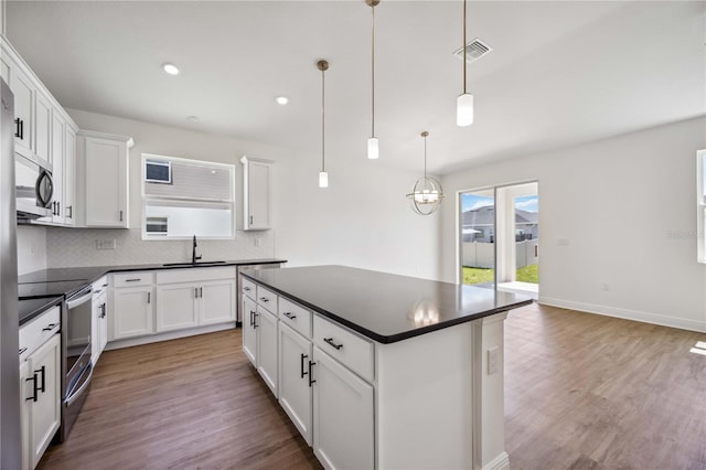 kitchen with stainless steel appliances, hanging light fixtures, decorative backsplash, sink, and light hardwood / wood-style floors