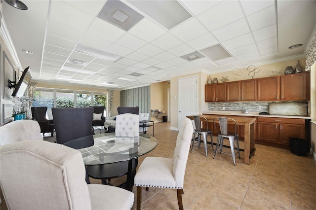 dining space featuring crown molding, light tile patterned floors, and a paneled ceiling