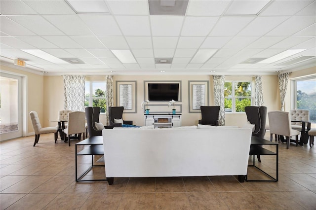 living room featuring a drop ceiling, tile patterned floors, and crown molding