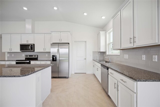 kitchen with lofted ceiling, stainless steel appliances, light tile patterned floors, and white cabinets