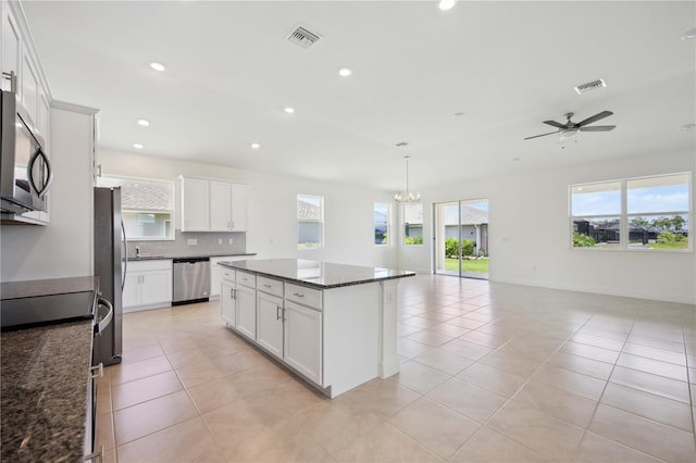 kitchen with white cabinetry, stainless steel appliances, backsplash, and a center island