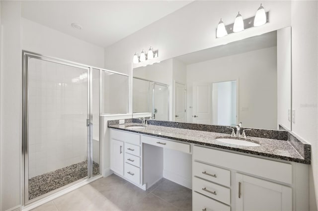 bathroom with dual vanity, a shower with door, and tile patterned flooring