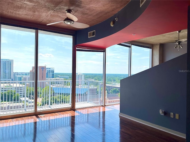 interior space with a wall of windows, ceiling fan, and hardwood / wood-style flooring