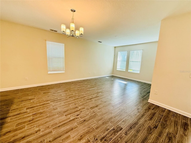 unfurnished room featuring hardwood / wood-style flooring and a notable chandelier