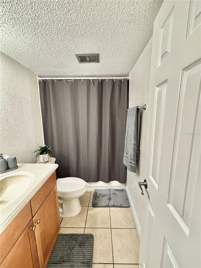 bathroom featuring vanity, a textured ceiling, tile patterned floors, and toilet