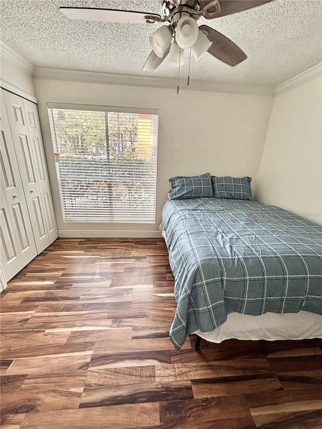 bedroom with ceiling fan, wood-type flooring, a closet, and a textured ceiling