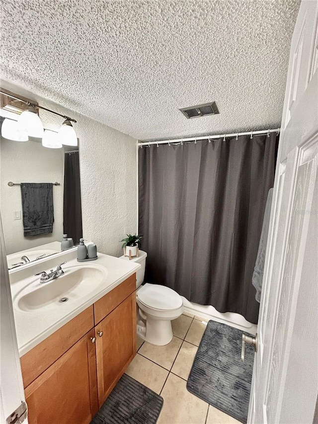 bathroom featuring tile patterned flooring, vanity, a textured ceiling, and toilet