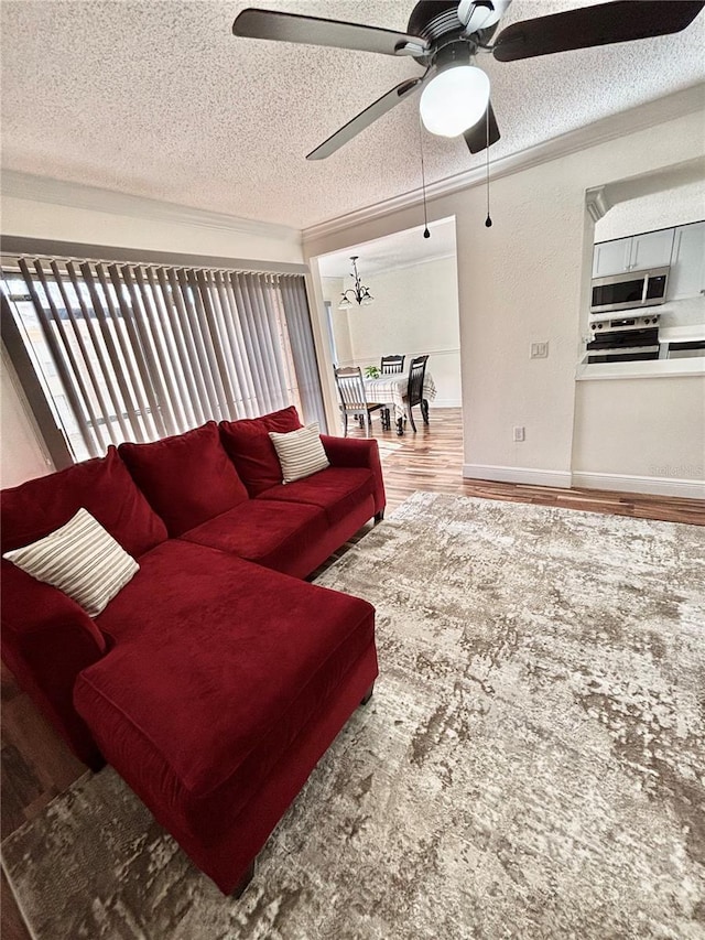 living room with hardwood / wood-style flooring, ceiling fan, ornamental molding, and a textured ceiling