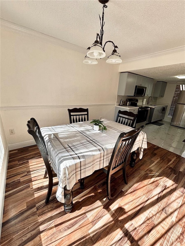 dining area featuring ornamental molding, wood-type flooring, and a textured ceiling