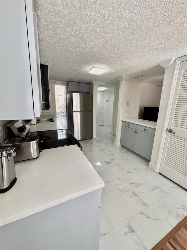 kitchen with stainless steel appliances, gray cabinets, and a textured ceiling