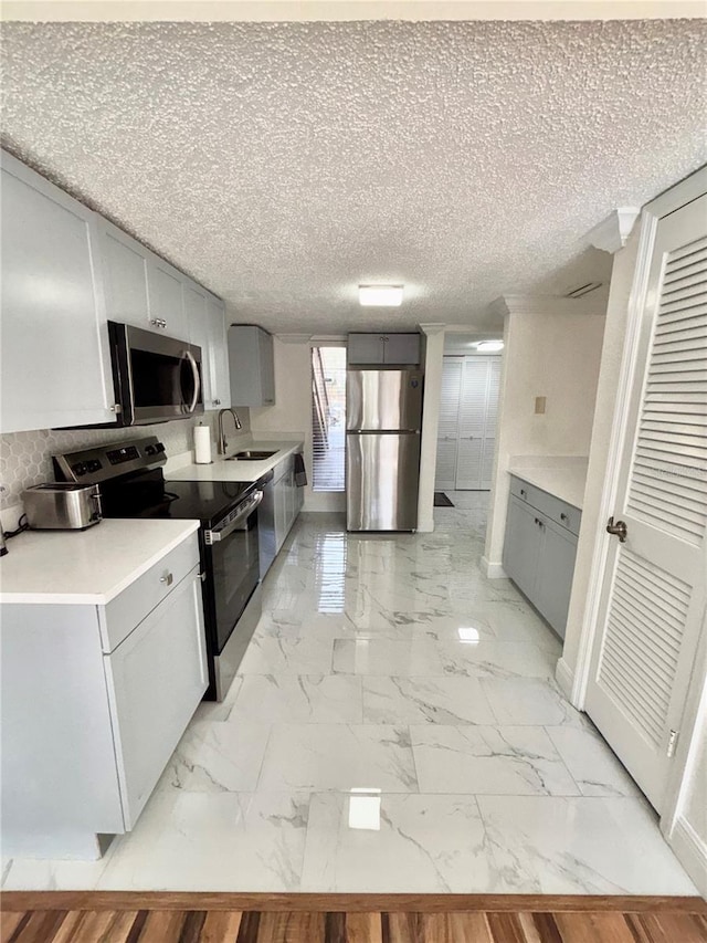 kitchen featuring gray cabinets, appliances with stainless steel finishes, sink, and a textured ceiling