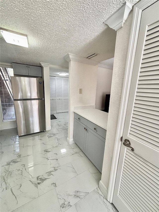 kitchen featuring gray cabinets, a textured ceiling, and stainless steel refrigerator