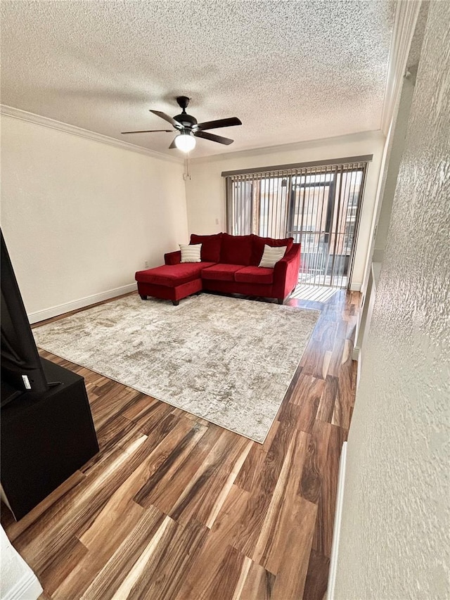 living room featuring wood-type flooring, ornamental molding, ceiling fan, and a textured ceiling