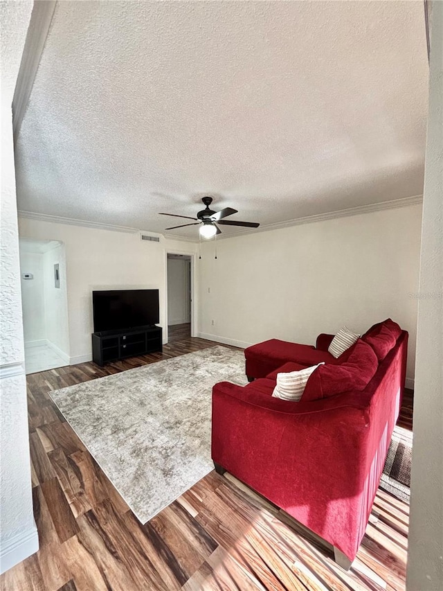 living room featuring ceiling fan, crown molding, wood-type flooring, and a textured ceiling