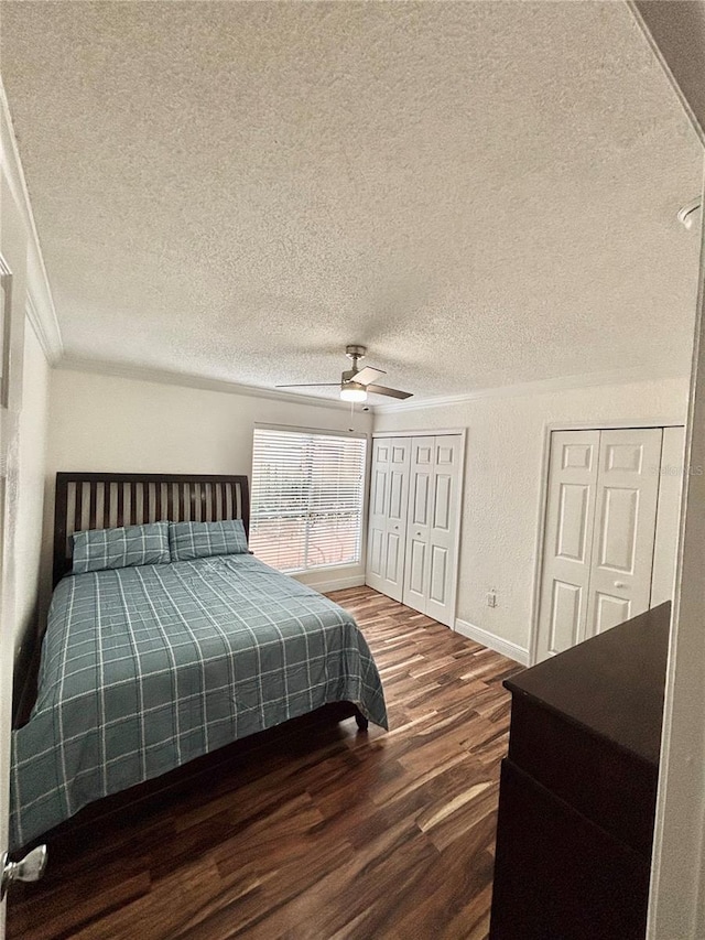 bedroom featuring multiple closets, wood-type flooring, a textured ceiling, and ceiling fan