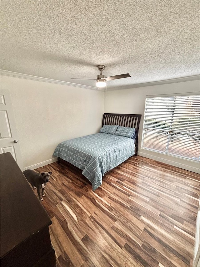 bedroom featuring wood-type flooring, ornamental molding, a textured ceiling, and ceiling fan