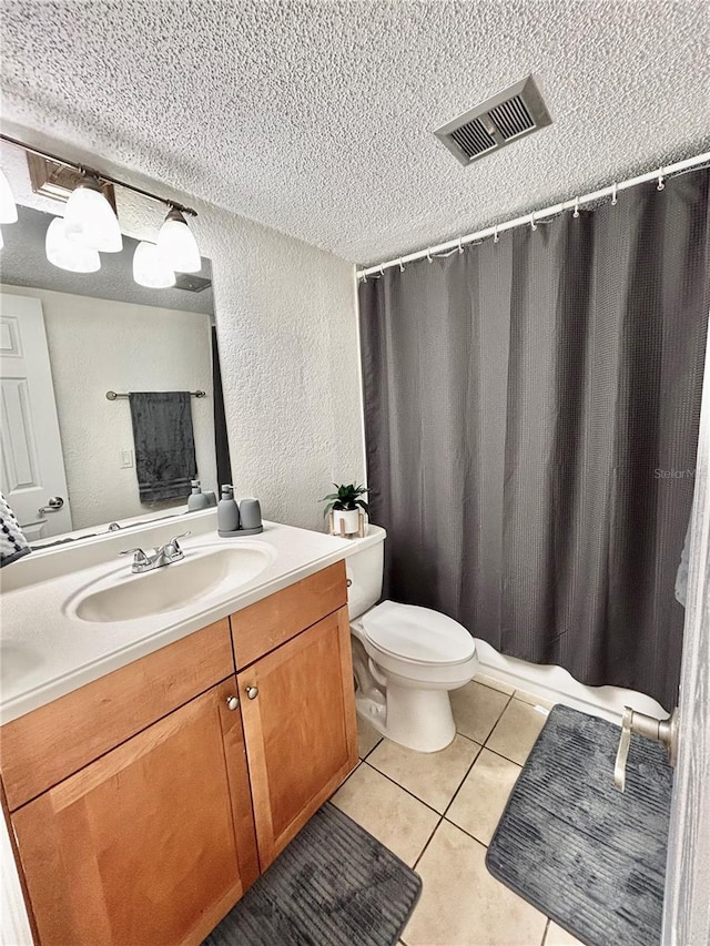 bathroom featuring vanity, toilet, tile patterned flooring, and a textured ceiling