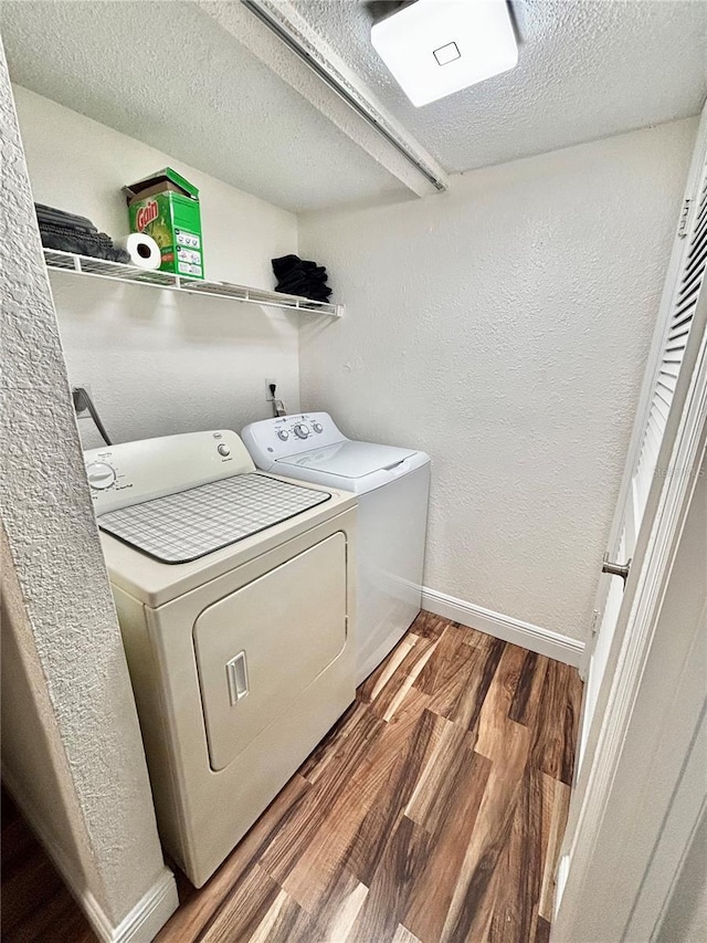 laundry room featuring washing machine and dryer, hardwood / wood-style floors, and a textured ceiling