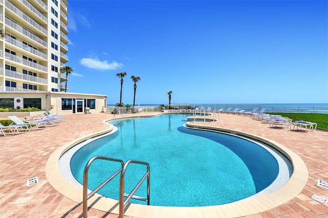 view of pool featuring a patio area and a water view