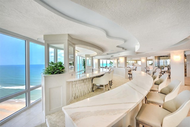 dining area featuring floor to ceiling windows, a textured ceiling, and a water view