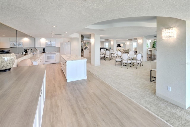 unfurnished living room with sink, a textured ceiling, and light colored carpet