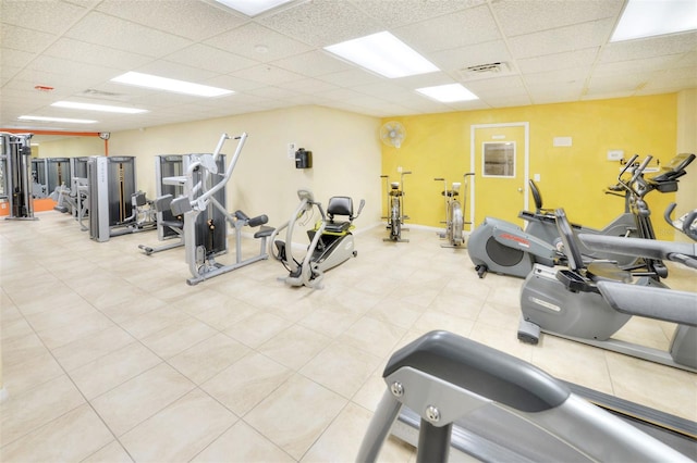 workout area featuring a paneled ceiling and light tile floors