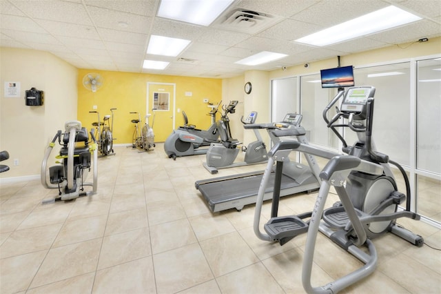 workout area featuring light tile floors and a drop ceiling