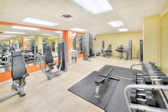 exercise room with light tile floors and a drop ceiling