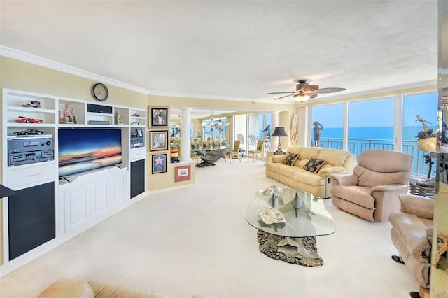 living room featuring crown molding, a water view, carpet floors, ornate columns, and ceiling fan