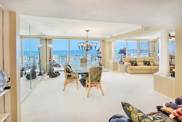 carpeted dining room featuring crown molding, a water view, ornate columns, floor to ceiling windows, and a chandelier